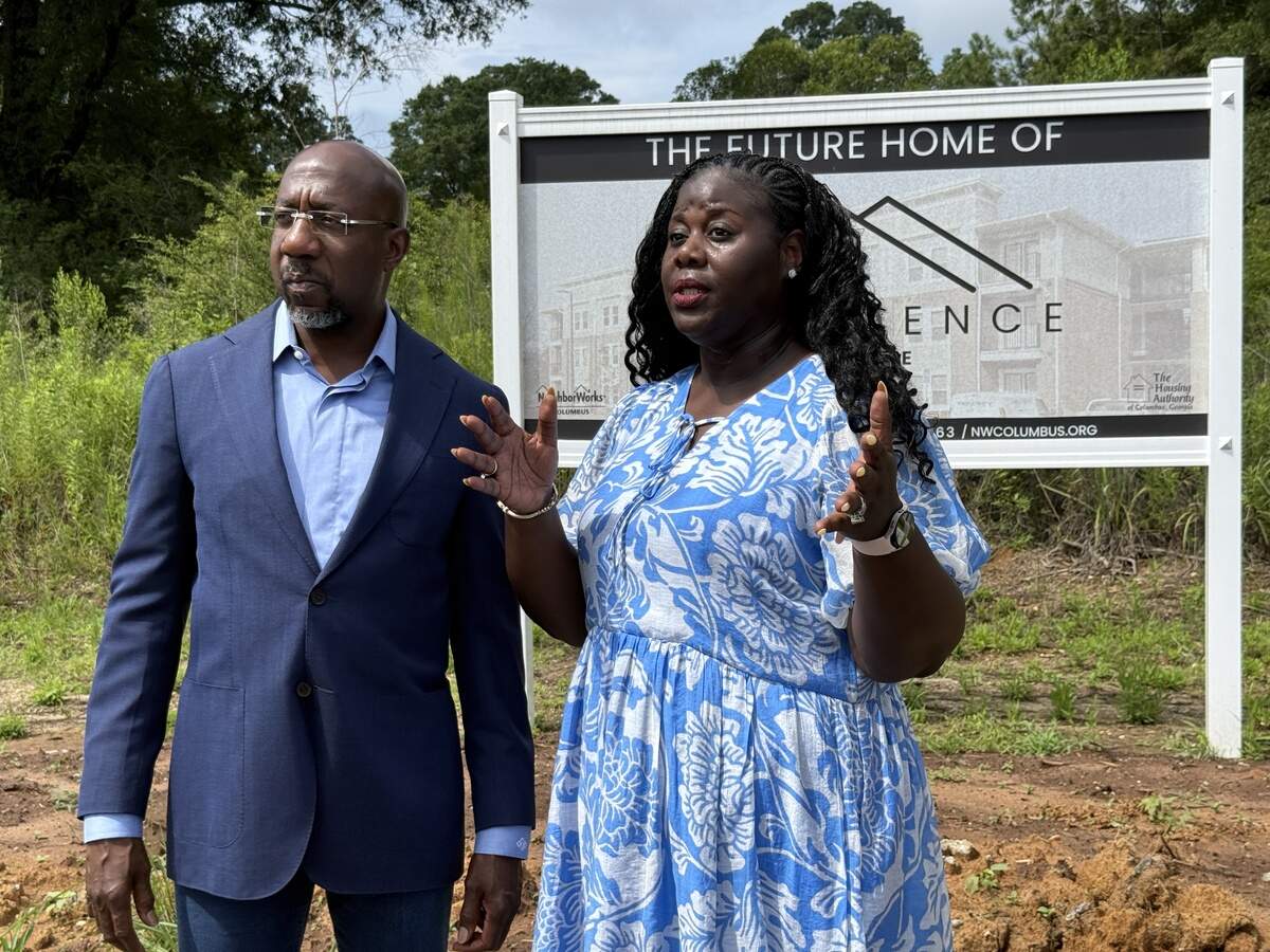 U.S. Sen. Raphael Warnock (D-Ga.) listens to a briefing from Kimberly Hinton-Poole, president and CEO of NeighborWorks Columbus, during his July 6, 2026, tour of Elliott’s Walk and sites of upcoming housing developments in Columbus.
