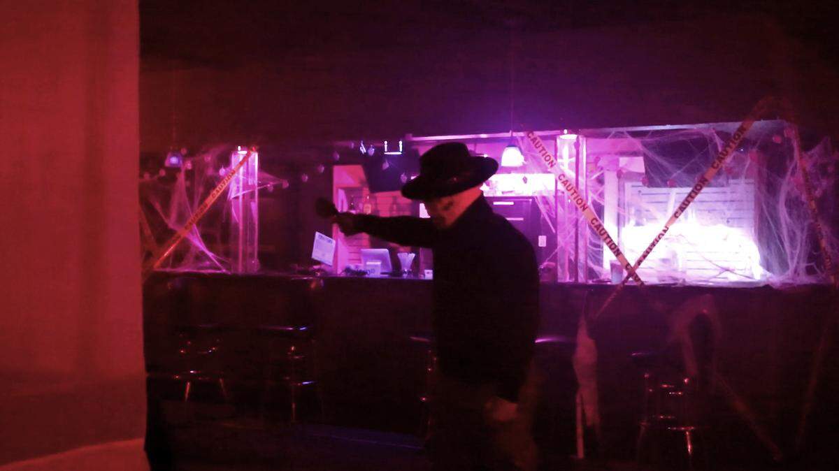 A bloodied actor directs visitors through the Quarantine Haunted House in Columbus, Ga. on Oct. 28, 2021.