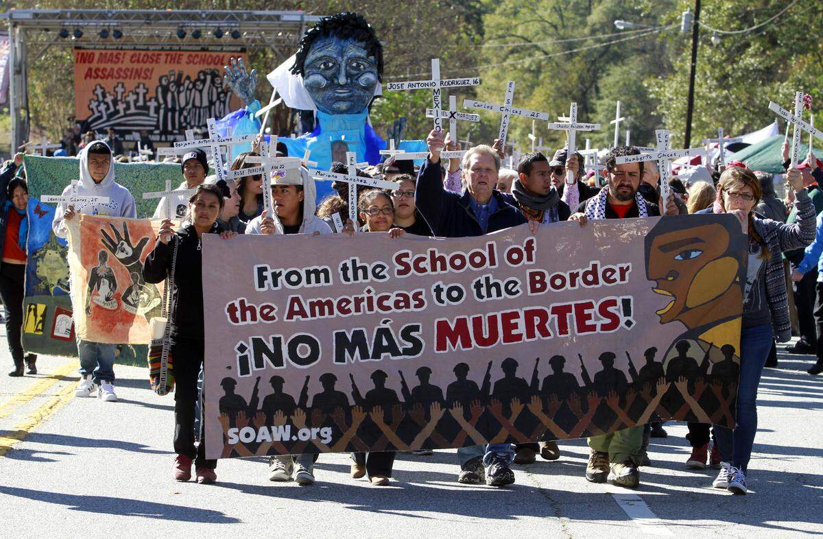 Roy Bourgeois, front center, joins others in marching at the SOA Watch protest at the gates of Fort Benning on Nov. 22, 2015.
