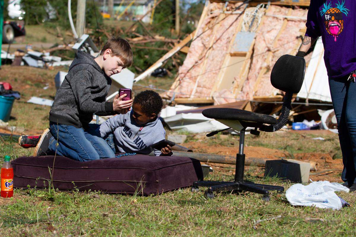 Bryson Hopper, 8, from Smiths Station, Al., and Mason McCoy, 4, from Motts, Al., lie on a couch cushion together while their families and friends try to find personal items from the overturned mobile home of Vickie Jones on Tuesday, March 5, 2019, in Smiths Station, Al. A tornado landed in the Smiths Station neighborhood on Sunday, March 3, 2019, but Jones and her son were not in their home when the tornado struck their mobile home.