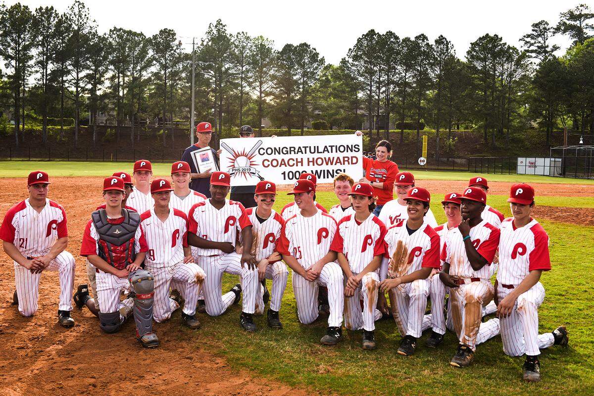 St. Anne-Pacelli head baseball coach Bobby Howard and the team pose for a group photo Monday afternoon after the Vikings defeated Webster County 8-3, giving Howard his 1,000th career win.