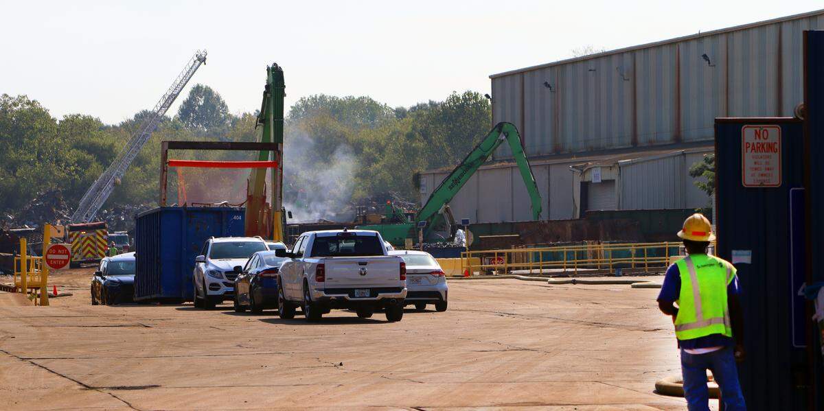 A Radius Recycling employee watches as fire personnel separate piles of smoldering metal on Tuesday morning.