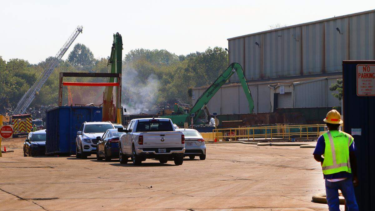 A Radius Recycling employee watches as fire personnel separate piles of smoldering metal on Tuesday morning.