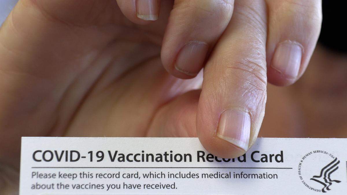 In this March 12, 2021, file photo, Jamie Smith, a teacher at Harris County Carver Middle School in Hamilton, Georgia, shows her vaccination card after receiving the Moderna COVID-19 vaccination from Kim Storey, the pharmacist in charge at Holmes Pharmacy in Hamilton, Georgia. Several Harris County School district employees were getting the shot as part of a partnership between the pharmacy and the school district.