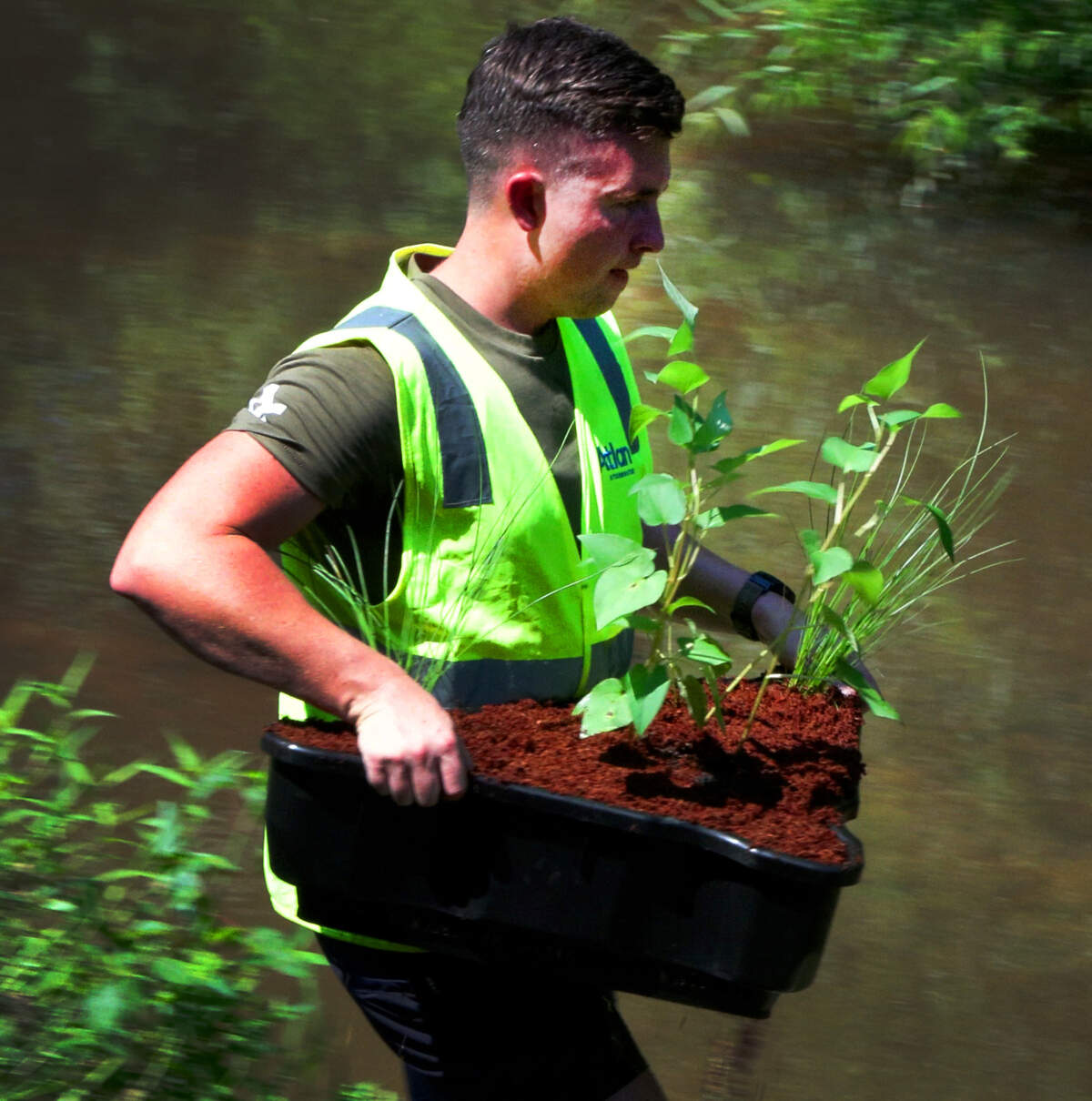 Toby Attwood of Atlan Stormwater carries a group of plants to a new trash trap Atlan installed at Cooper Creek Park in Columbus, Georgia. 06/23/2025
