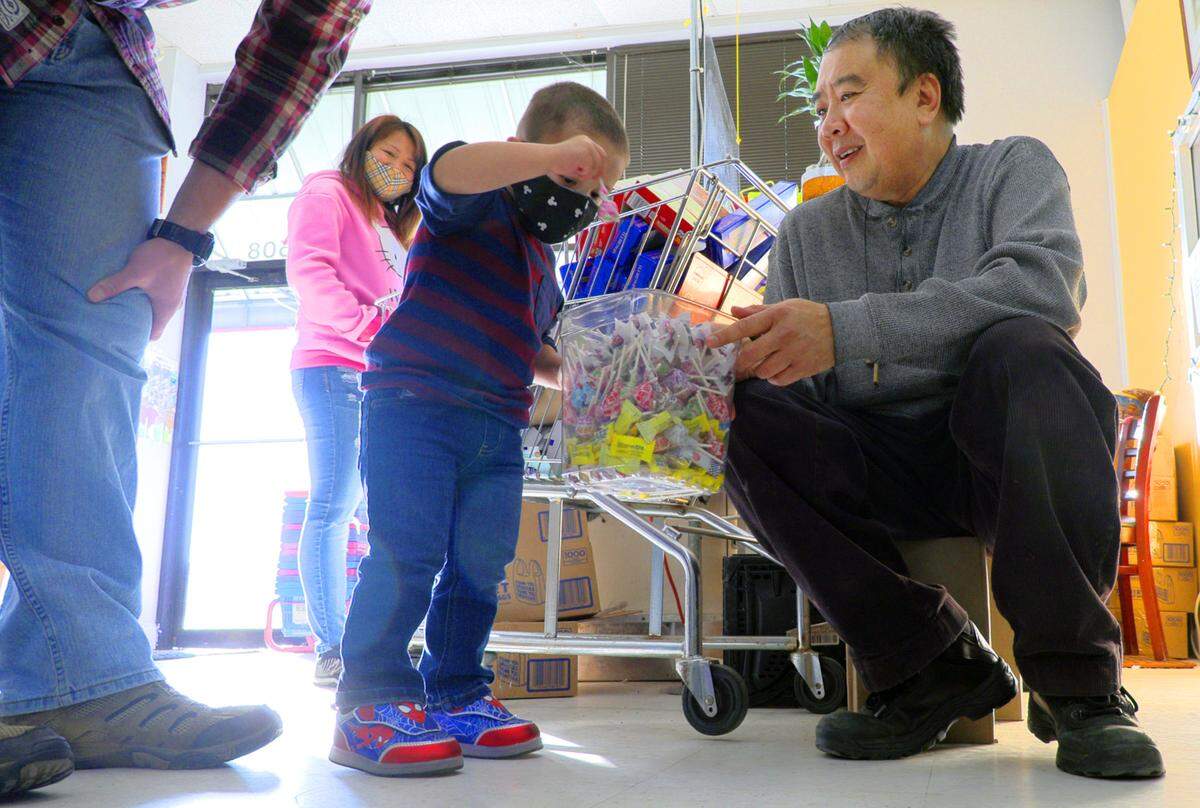 Tuan Clay, right, owner of Oriental Food & Gift at 4508 Armour Road, in Columbus, lets a young customer select a free piece of candy.