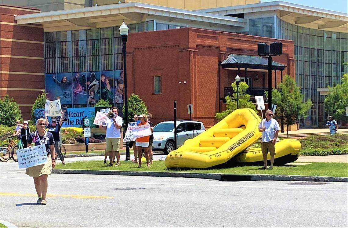 About 10 protesters stand in the median at Broadway and 10th Street in downtown Columbus on June 10, 2023, to demonstrate against former president Donald Trump, who spoke later in the afternoon at the Columbus Convention & Trade Center during the Georgia Republican Party’s State Convention.