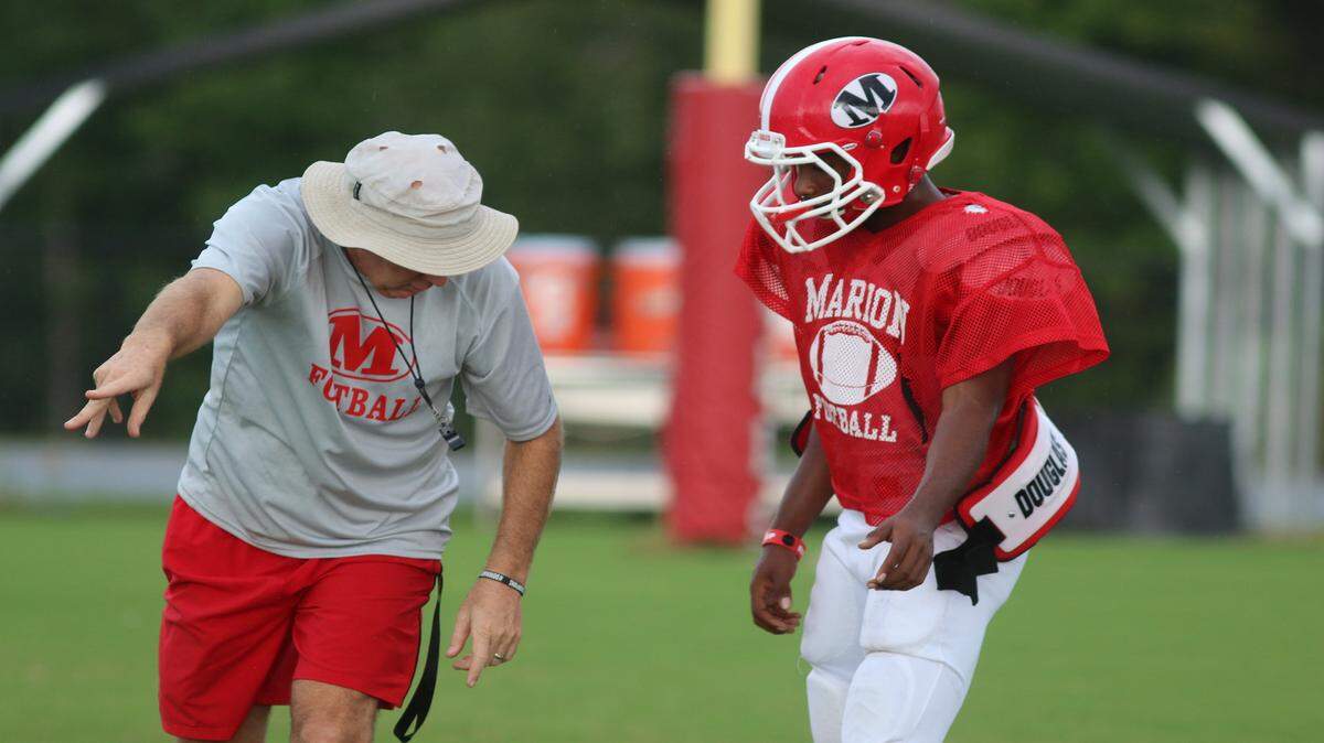 Coach Mike Swaney and quarterback Quentez Battle discuss his mechanics during practice Sept. 8 at Marion County.