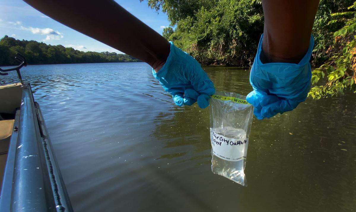 Vanisha Estrahota, Columbus technical programs fellow, takes a water sample from the Chattahoochee River near the outfall pipe for Phenix City, Alabama’s wastewater treatment plant. 07/10/2024