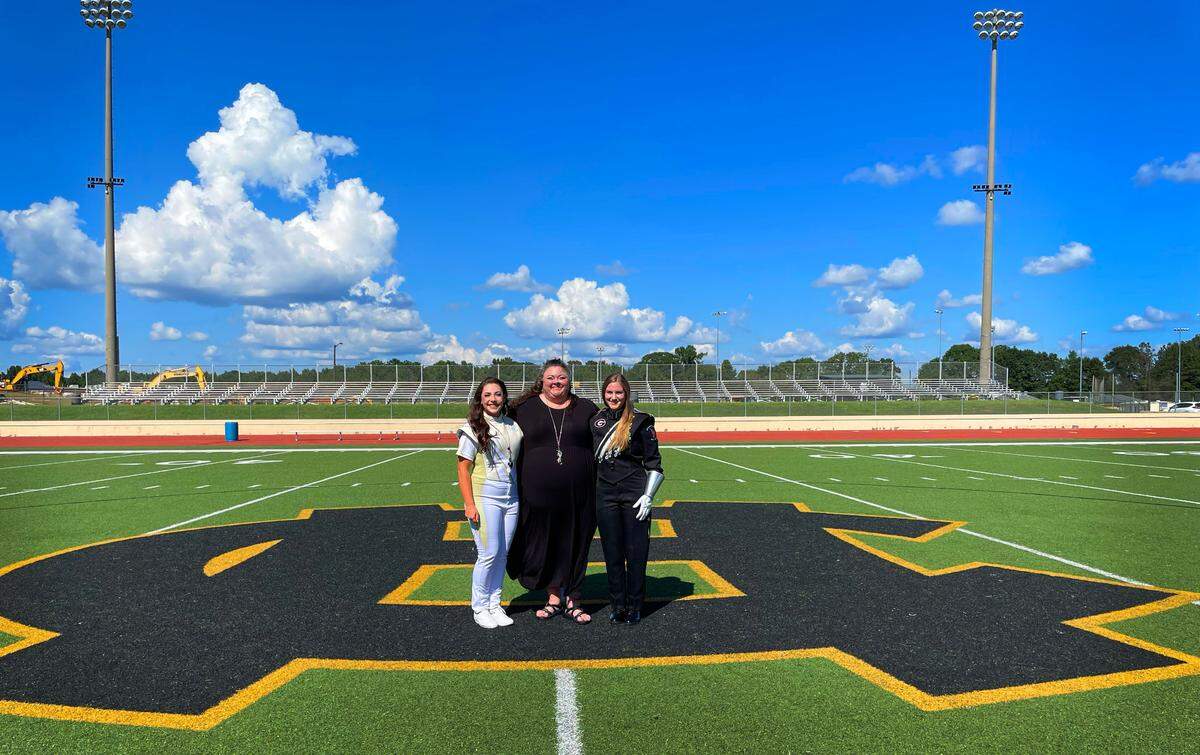 Georgia Tech drum major Kaleigh Griswell, left, and University of Georgia drum major Hannah Marston, right, are Harris County High School graduates. They returned to HCHS for a photo session Aug. 28, 2022, with HCHS band director Miranda Carlsen, center, to celebrate their success.