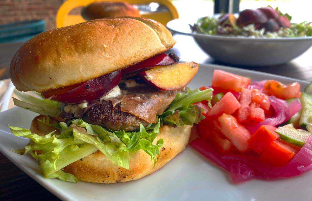 The Clingstone Classic Burger, left, at The Food Mill in Columbus is topped with clingstone peaches. It’s among the specials The Food Mill is offering this week that include clingstone peaches. 05/28/2025