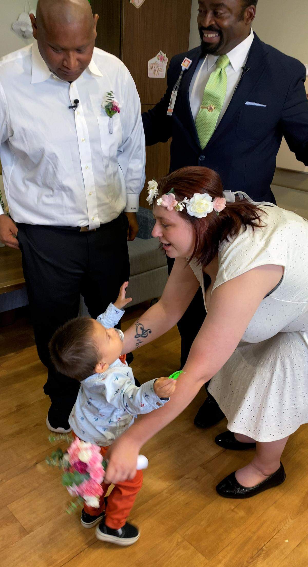 Alexander Santos,left,watches his wife Heather lift up their two-year-old son Noah after they were married at Piedmont Columbus Regional’s Midtown Campus Wednesday afternoon. Pastor Marlon Scott, standing right, officiated. 07/20/2023
