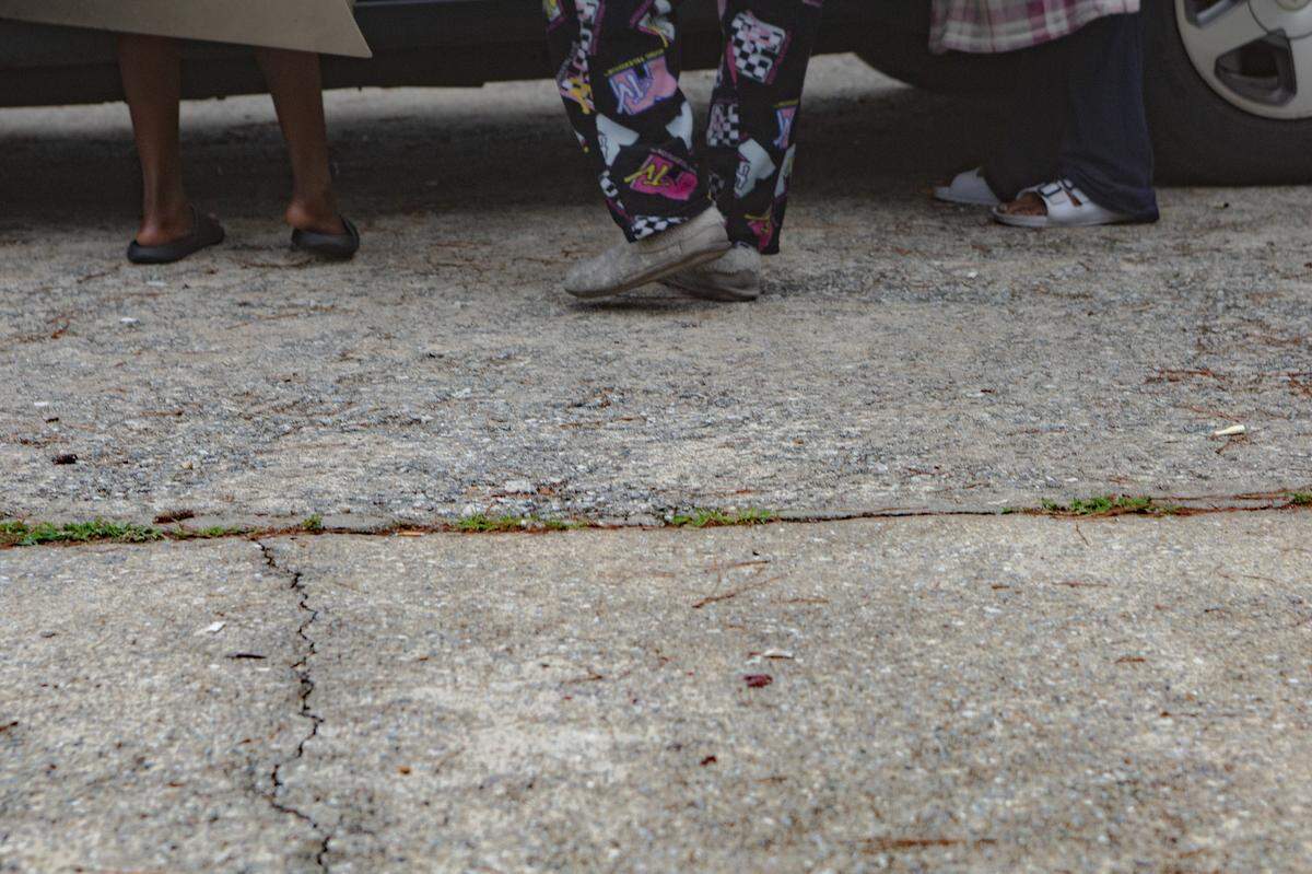Tenants wait in the parking lot as their home is cleared during an eviction on July 20, 2021, in Columbus, Ga. Their belongings are piled into a parking space of the apartment building.