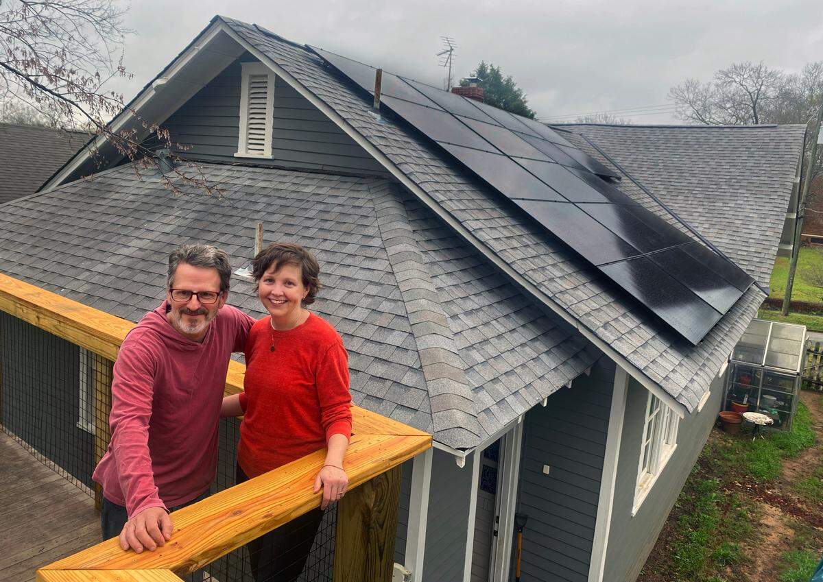 Brad Barnes and Jenn Collins on their deck near their newly installed solar photo voltaic (pv) panel system through Georgia BRIGHT( (Building Renewables, Investing for Green, Healthy, Thriving Communities). 17 panels face the southern slope of their home ready to absorb the solar energy. 03/06/2024