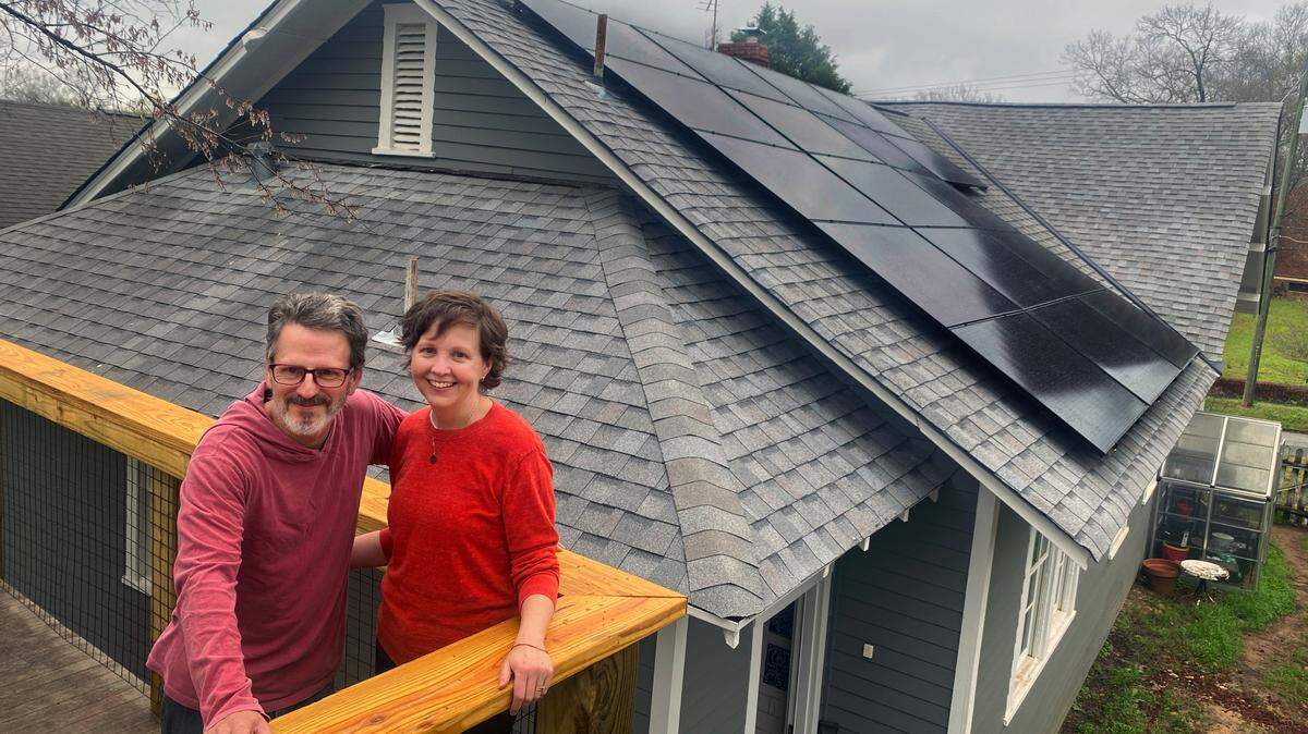 Brad Barnes and Jenn Collins on their deck near their newly installed solar photo voltaic (pv) panel system through Georgia BRIGHT( (Building Renewables, Investing for Green, Healthy, Thriving Communities). 17 panels face the southern slope of their home ready to absorb the solar energy. 03/06/2024
