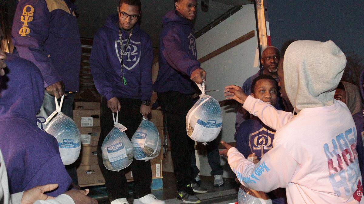 Members of the Lambda Iota and Nu Delta Chapters of the Omega Psi Phi Fraternity, Inc., and the Omega Lamplighters youth leadership organization hand out turkeys to families in need Tuesday at the Georgia Department of Labor parking lot. The fraternity brothers pitched in to buy 300 turkeys in the spirit of the organization’s community outreach efforts.