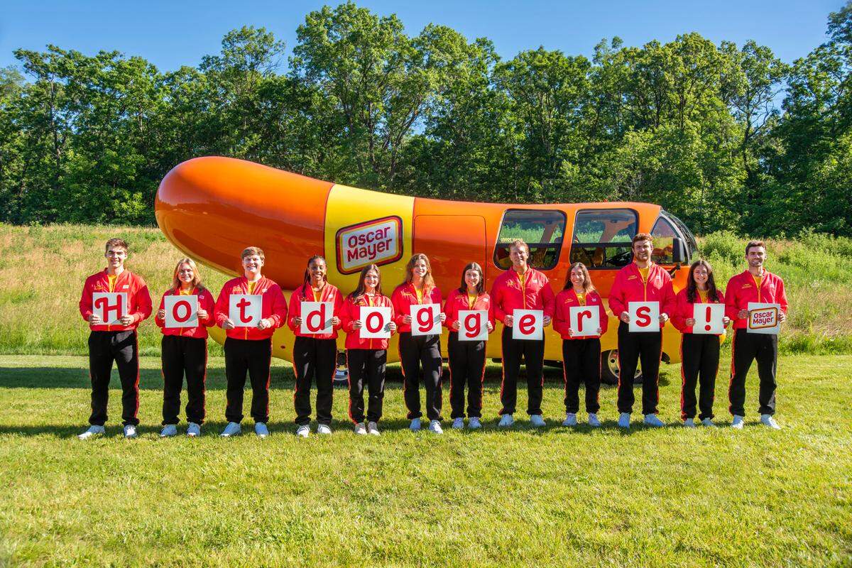 Out of more than 7,000 applicants for the 2024-25 season, Oscar Mayer selected these 12 Wienermobile drivers, including Columbus native Sarah Oney (seventh from left). They are spelling the word “Hotdoggers,” the title for Wienermobile drivers, as they pose in Madison, Wisconsin, where they trained for two weeks in June 2024.