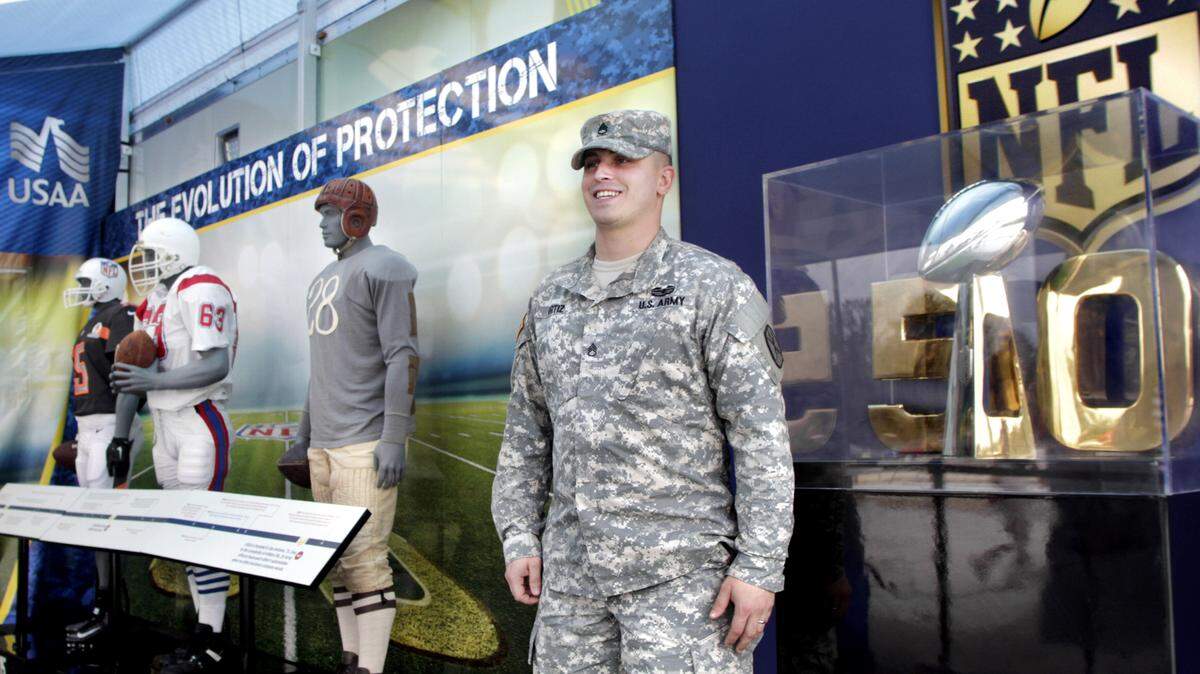 ROBIN TRIMARCHI/rtrimarchi@ledger-enquirer.comStaff Sgt. Brett Ortiz stands next to a traveling replica of the Vince Lombardi Trophy on display at the Fort Benning AAFES Exchange on Thursday.