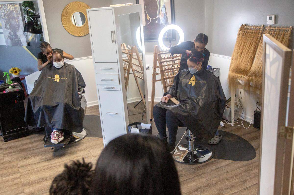 Stylists Taniesa Taylor and Jamie Scott work on clients’ hair at Locs, Twists, Braids and Crochets on Feb. 10, 2021, in Columbus, Ga.
