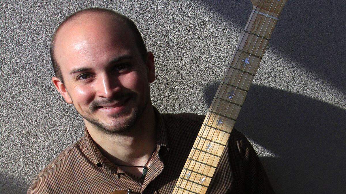 Frank Schley IV holds a “Damcaster,” an electric guitar he built from wood taken from the former dams on the Chattahoochee River.