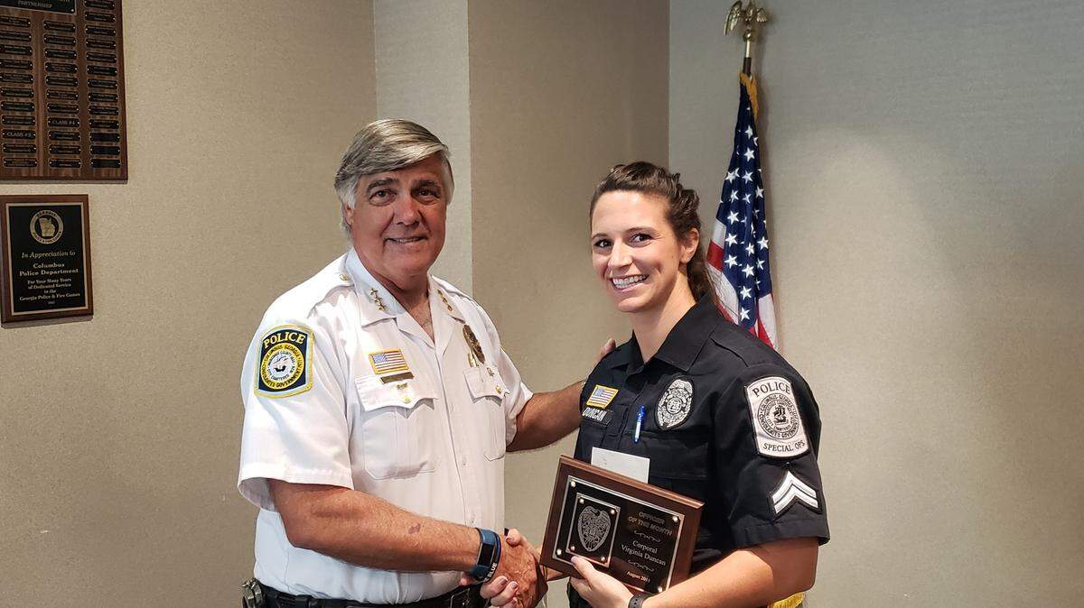 Cpl. Virginia Duncan is presented a plaque for Officer of the Month for August 2018 from Assistant Police Chief Gil Slouchick .