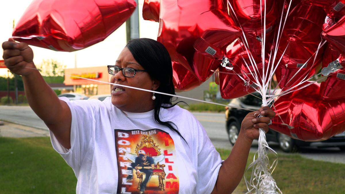 Tanya Weaver, the mother of Dontrell Williams, hands out balloons to those gathered April 27, 2021 at the Circle K convenience store at 5448 Forrest Rd. in Columbus, Georgia to remember what would have been Williams’ 28th birthday. Dontrell Williams was shot and killed in 2019 while working an overnight shift at this same store.