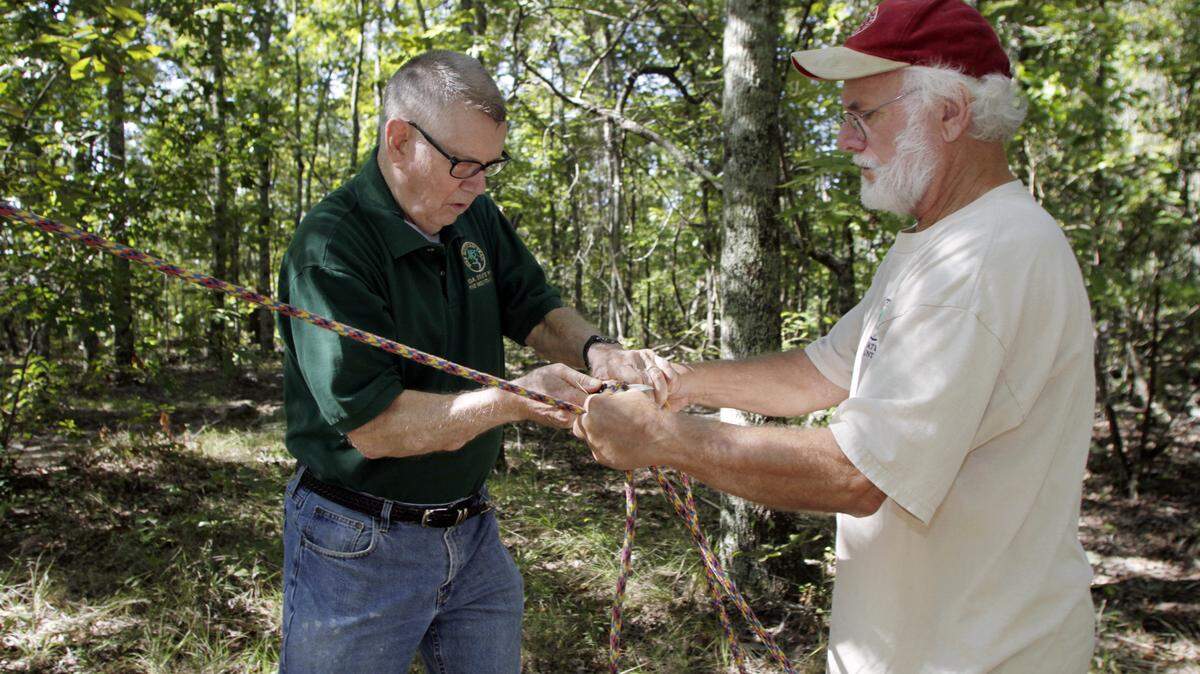 ROBIN TRIMARCHI rtrimarchi@ledger-enquirer.com 
 Carl Carlson, left, and Jim Hall secure a rope before they cut down a dead tree that is a threat to fall at the Dowdell Knob trail head. A group of Pine Mountain Association volunteers gathered to clear and clean up the trail on a Saturday morning. Carlson, the trail maintenance supervisor for 20 years, is battling Parkinson's disease. F.D. Roosevelt State Park has 42 miles of trails that the volunteers maintain. 09.19.15