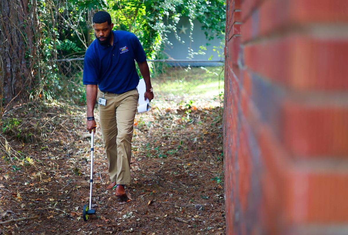 Lorenzo Dowdell Jr., a residential property appraiser with the Columbus Consolidated Government, measures the exterior dimensions of a house in Columbus on June 13, 2025.