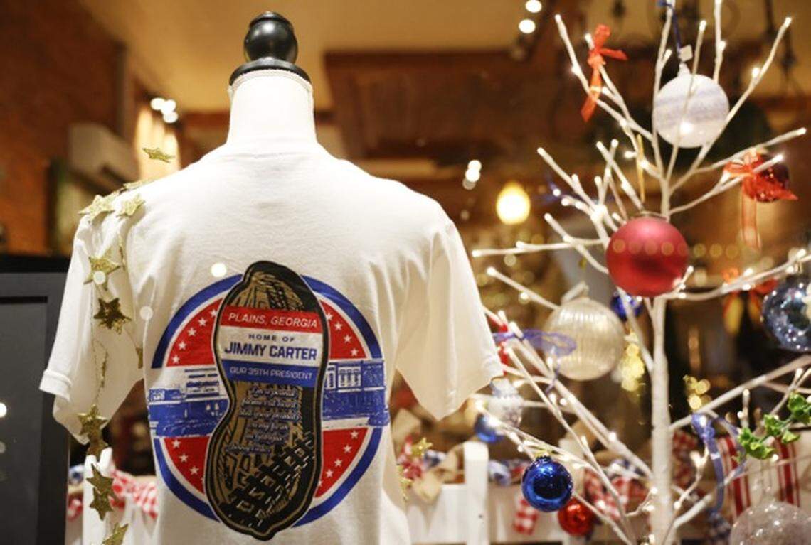 Jimmy Carter t-shirts hang in Plains Sweet Stems on Main Street in downtown Plains, Georgia on the evening of former president Jimmy Carter’s death on Sunday, Dec. 29, 2024, in Plains. The shop’s co-owner Jilliann Williams sais she came to set up more shirts in the shop this evening after hearing of Carter’s death, and in preparation for those that will come into town over the next several days to pay respects.