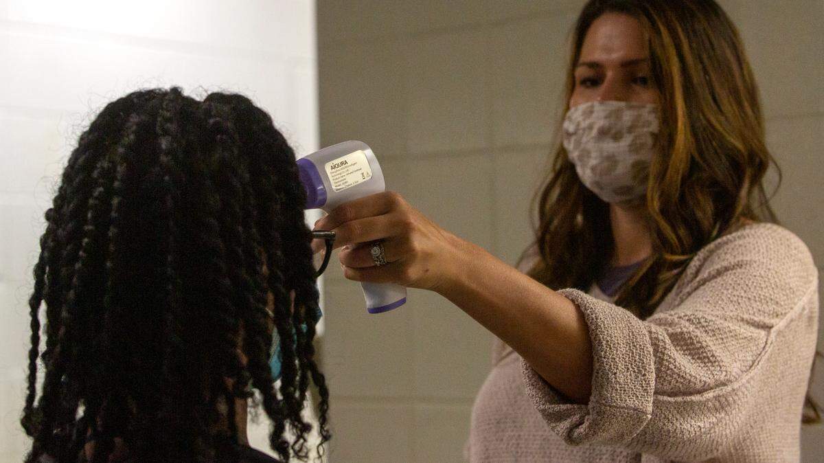 A teacher takes a student’s temperature before first period begins at Central High School on Tuesday, August 18, 2020 in Phenix City, Ala.