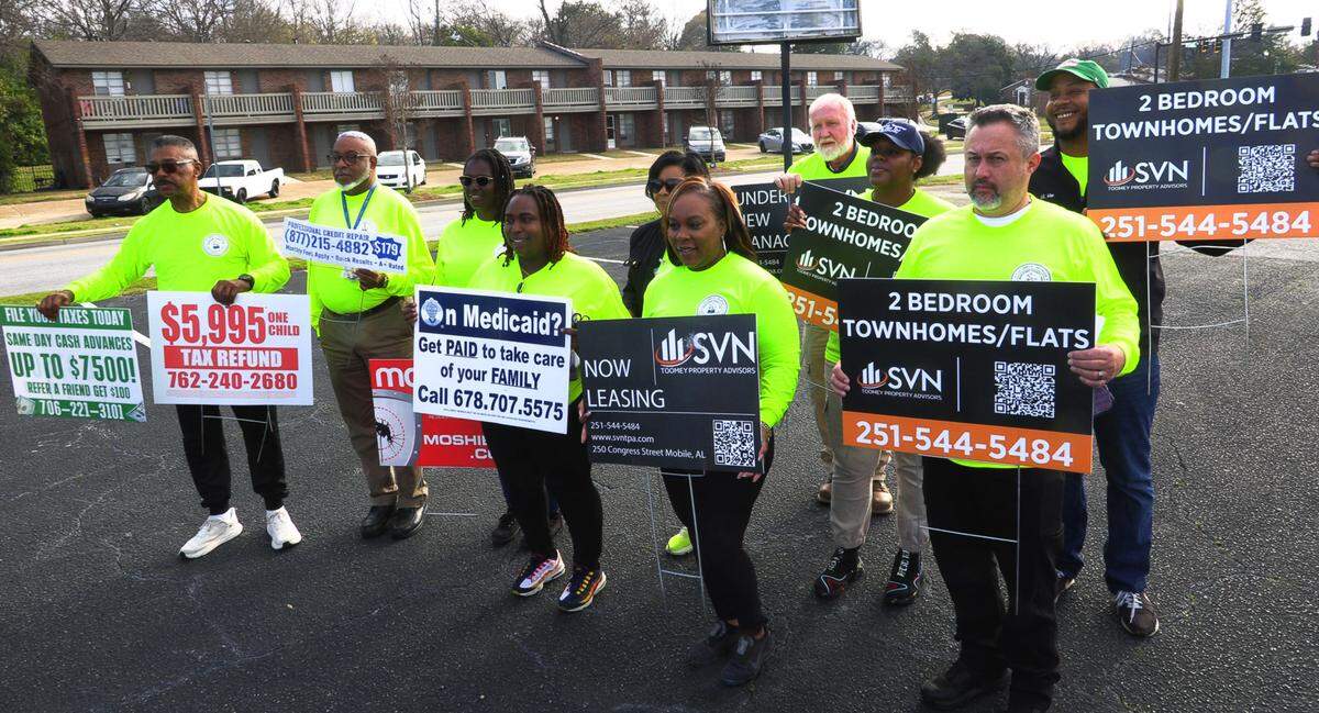 Columbus city manager Isaiah Hugley, far left, and other city employees gather Thursday morning for a group photo to show some of the illegally placed signs on the city right-of-way collected as part of the first “Operation Illegal Sign Roundup Campaign.” 02/27/2025