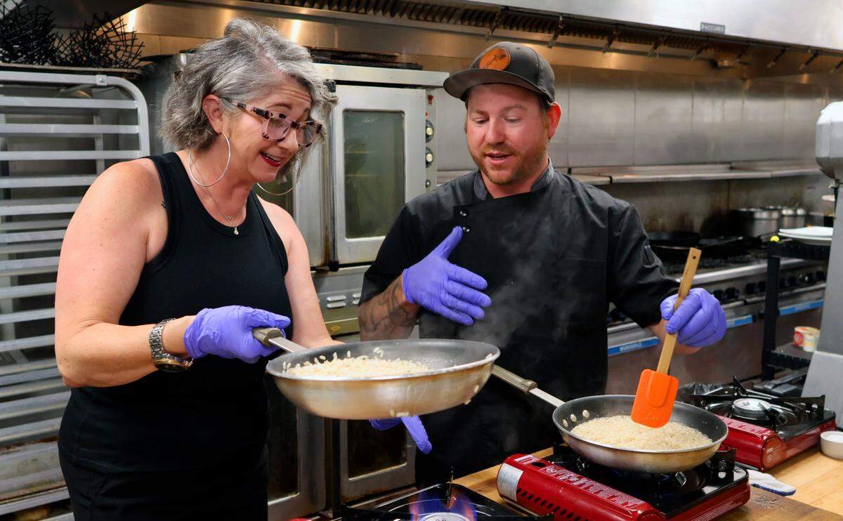 Chef Trevor Morris tries to teach Ledger--Enquirer report Sundi Rose how to flip the risotto in 2024.