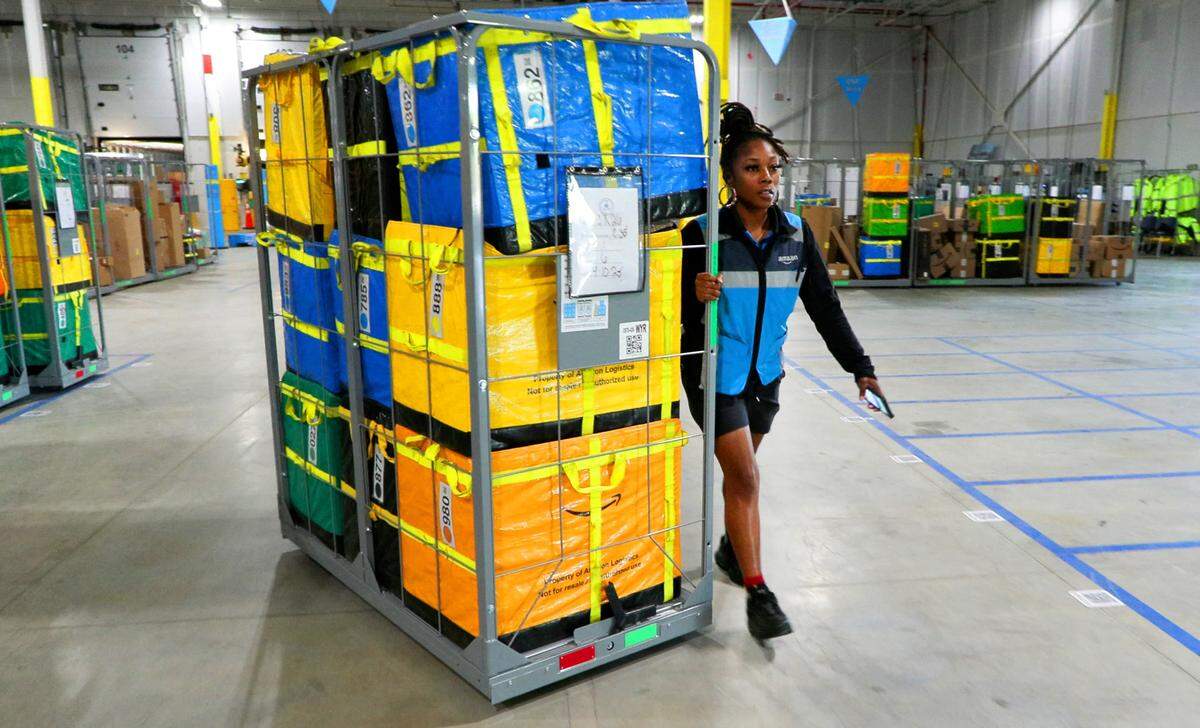 A delivery driver takes a load of boxes to her delivery truck at Amazon’s new 90,000-square-foot delivery station in Columbus, Georgia, in this April 2025 photo.