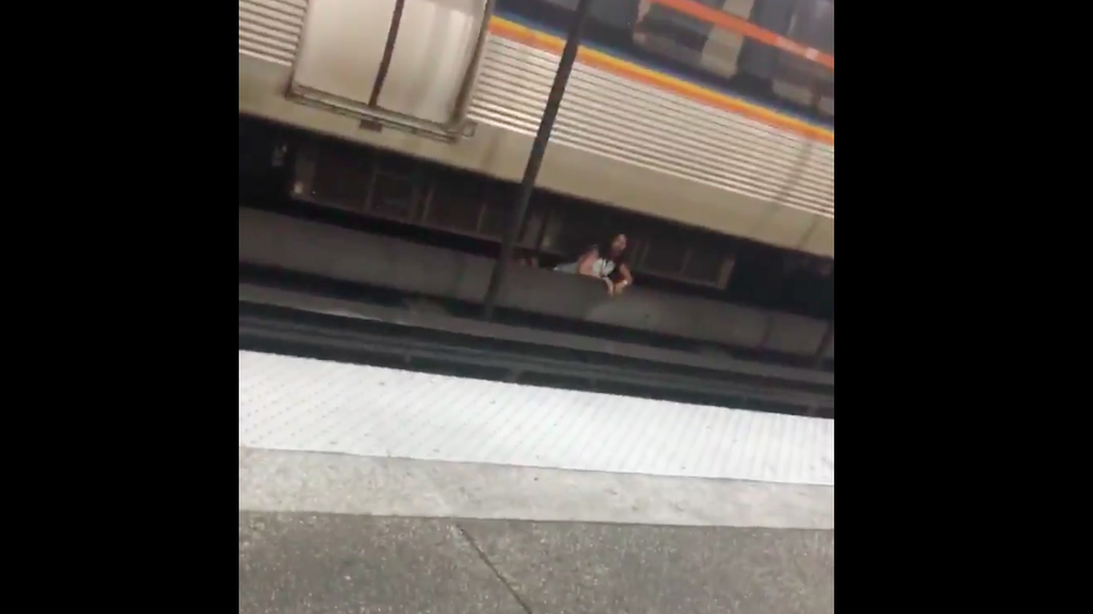 A woman begins crawling out from under a MARTA train after officials say someone was pushed onto the platform.