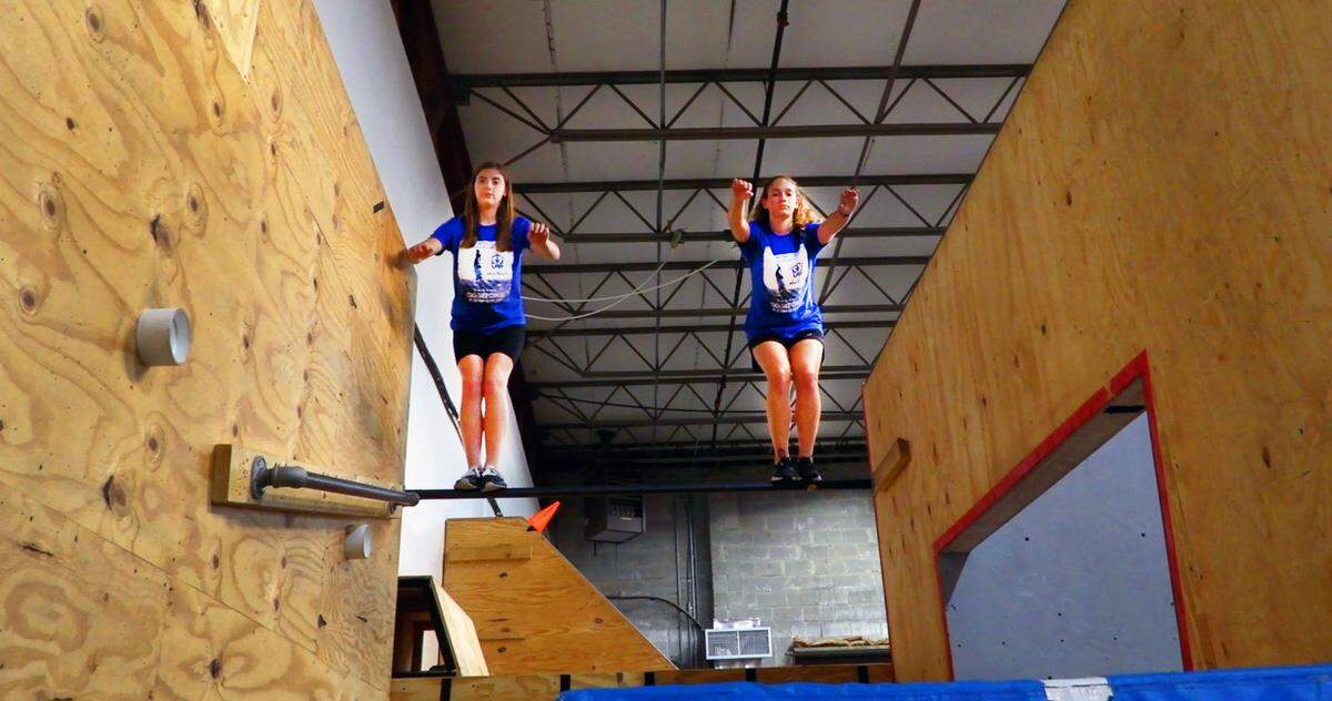 Jordan Watson, left, and Jodi Behar, balance on a bar at Level Up Parkour Academy in Columbus, Georgia.