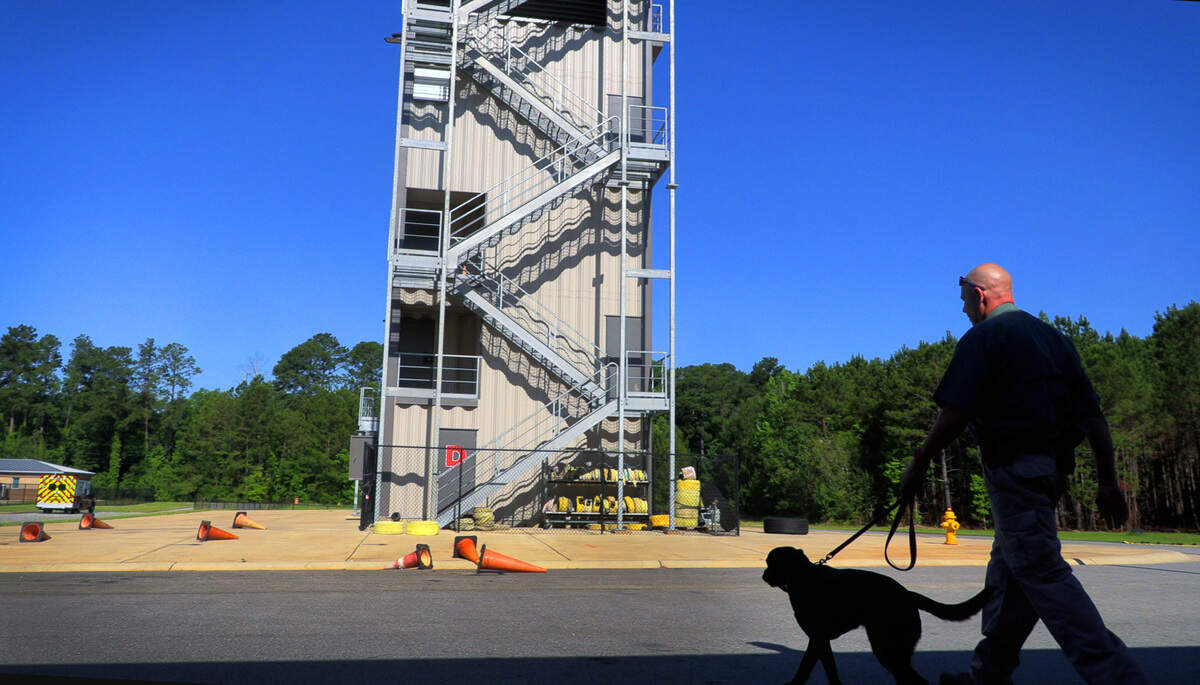 Sgt. Robert Collins, a fire investigator with Columbus Fire and Emergency Medical Services in Columbus, Georgia, and Carter walk to a training facility for an exercise demonstrating Carter’s ability to find accelerants by scent. 06/08/2022
