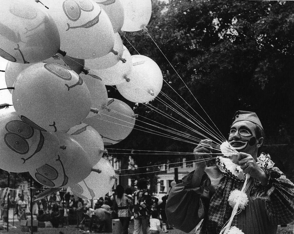 A clown wrangles several balloons at Salisbury Fair.