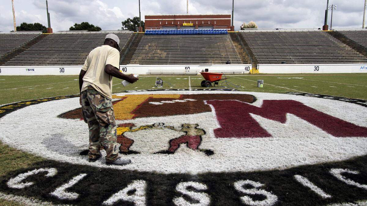 Photos by ROBIN TRIMARCHI/rtrimarchi@ledger-enquirer.comKelvin K.T. Thomas paints the mid-field logo Friday for the 80th Tuskegee-Morehouse Classic football game that will be played at A.J. McClung Memorial Stadium today. Thomas and his coworker Jimmy Pie Back Jackson paint football fields through their company Color on Grass.