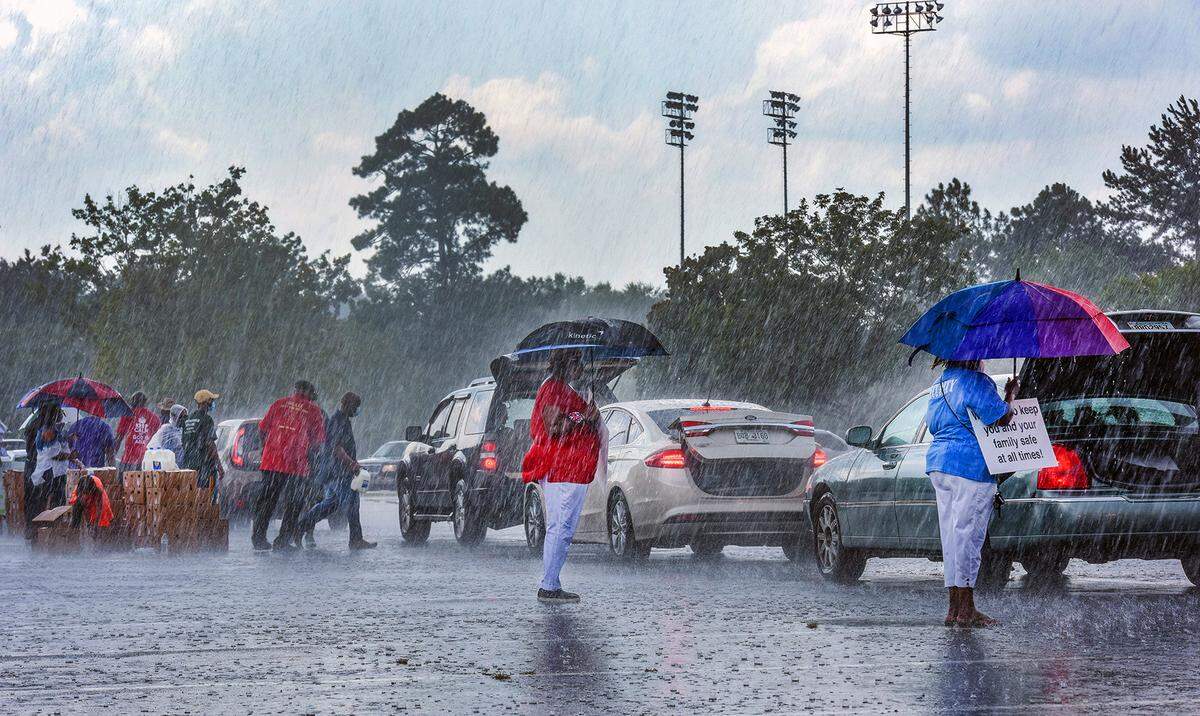 Volunteers worked through an afternoon thunderstorm to load boxes of meats, vegetables, and dairy products into cars during the Community Food Giveaway hosted by the Fourth Street Missionary Baptist Church, Saturday afternoon, August 8, 2020 in the parking lot of the Columbus Civic Center in Columbus, Georgia.