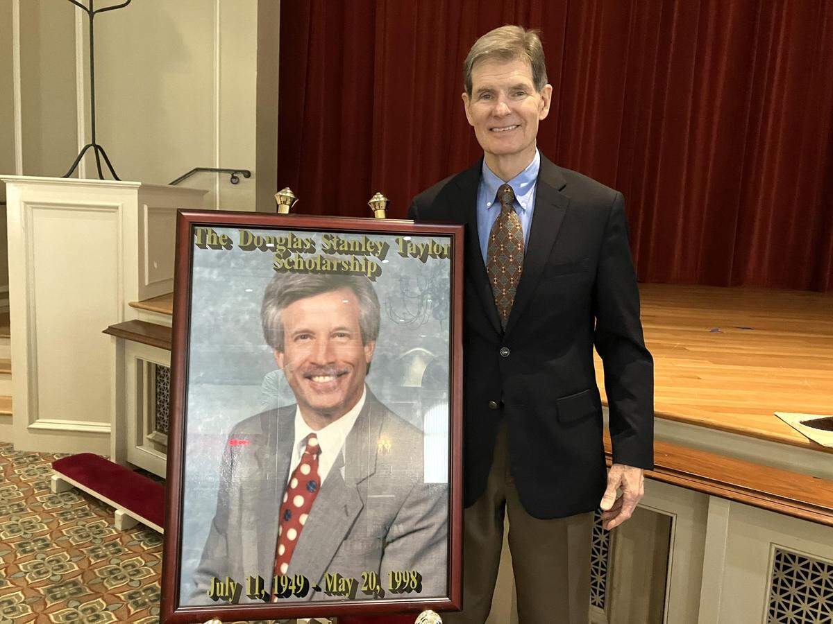 Ron Richardson, right, is co-trustee of the Douglas Stanley Taylor Scholarship Fund. He posed with a portrait of Taylor after the Jordan Vocational High School Senior Luncheon at the St. Luke Ministry Center in Columbus on May 15, 2025.