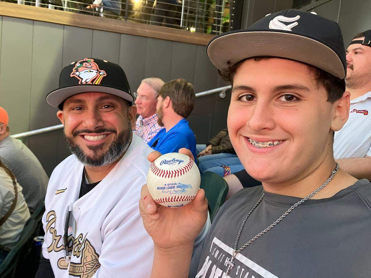 Cooper Savarese, 14, of Smiths Station shows the foul ball he will take home as a souvenir, thanks to his father, Chris, who bought two of the last four seats they saw available on a secondary market website just 3 hours before the Columbus Clingstones home opener at Synovus Park, the first game in the renovate stadium’s history.