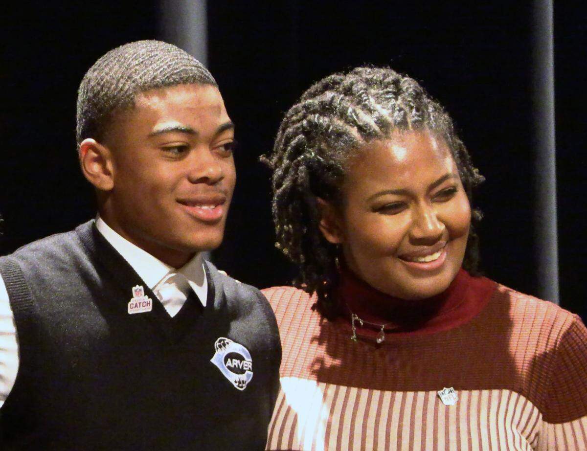 George Washington Carver High School junior Braylon Jakes, left, learned during Friday’s assembly that the NFL is providing two tickets for him and a guest to attend Super Bowl LVIII in Las Vegas. He was nominated by Kalin Tate, right, a 2014 Shaw High School graduate who is the NFL’s sponsorship coordinator. 11/03/2023