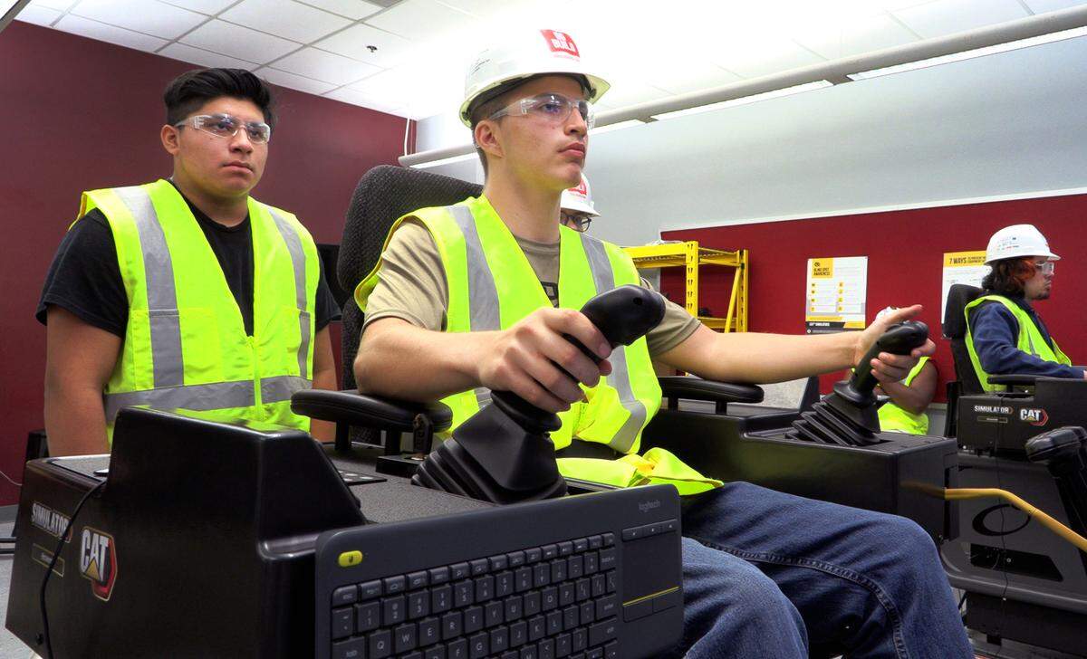 Kevin Hunt, 17, a junior at Jordan Vocational High School, center, works on a CAT Simulator as part of the school’s Heavy Equipment Operator Training Program. 09/23/2022
