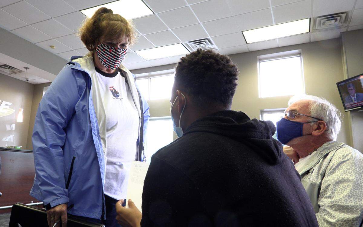 Rita Ellis,left, and Danny Ginter, right, both of Paz Amigos, speaks with one of several men recently released from the Stewart Detention Center at Groome Transportation in Columbus, Georgia. The men were preparing to take a shuttle van to Hartsfield-Jackson Atlanta International Airport.