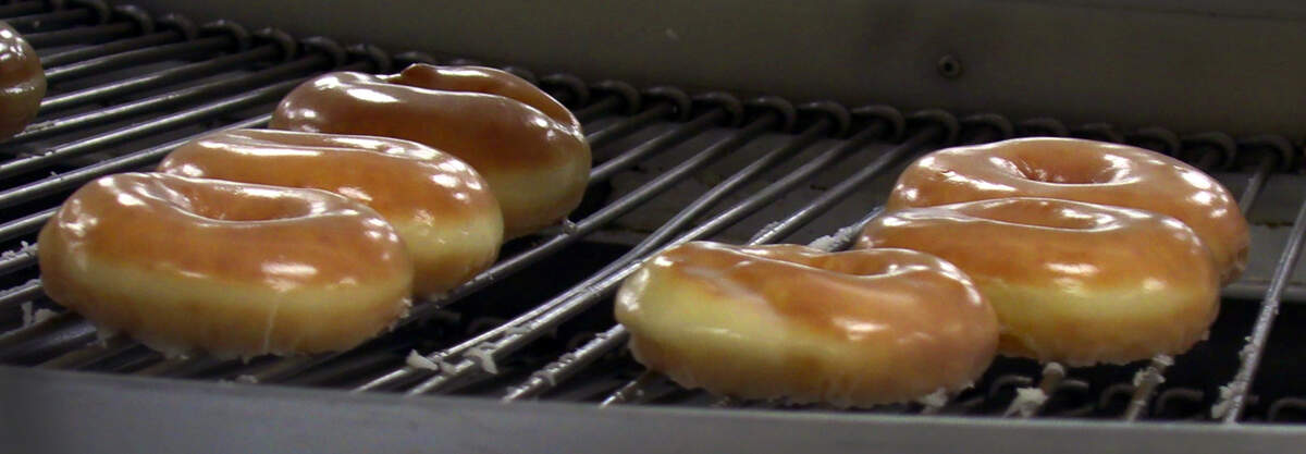 Hot, glazed doughnuts come down the production line Monday morning at Golden Donut in Columbus, Georgia. Golden Donut reopened Monday at 6 a.m. Walk-up customers were lined up outside the front doors, and drive thru traffic spilled out onto Manchester Expressway, before the opening. 08/02/2021