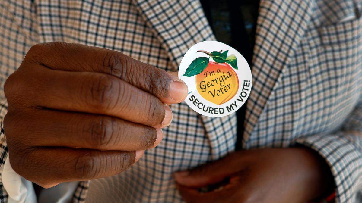 A voter shows the sticker she received after voting Tuesday morning at the Columbus Public Library in Columbus, Georgia. 05/21/2024