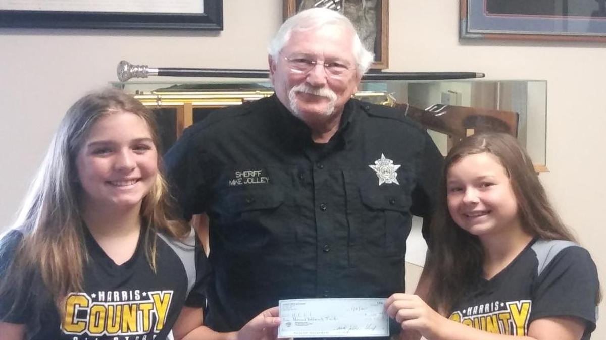 Harris County sheriff Mike Jolley donates to the Harris County All-Star softball team, much to the delight of players Mallory Hayes (left) and Annalise Knop (right).