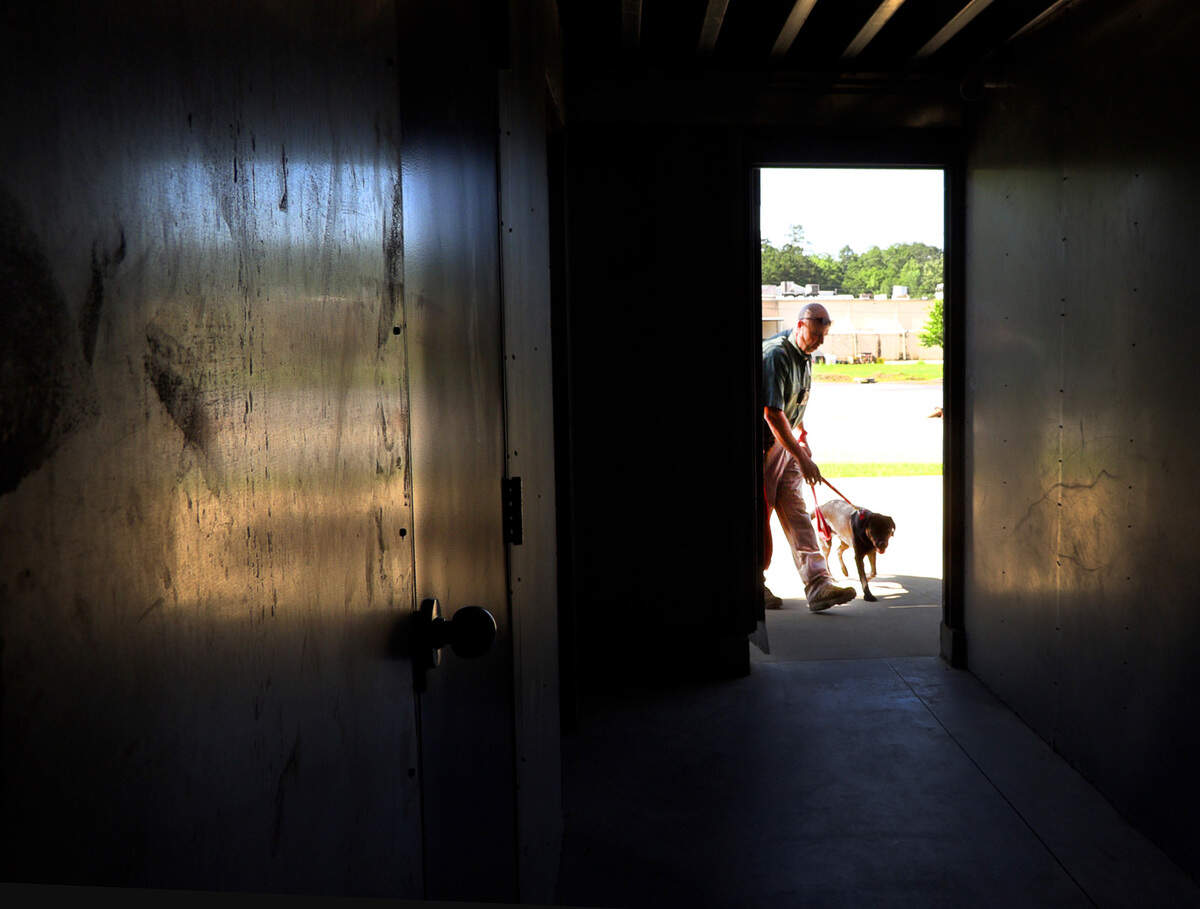 Sgt. Robert Collins, a fire investigator with Columbus Fire and Emergency Medical Services in Columbus, Georgia, and Carter enter a training facility during an exercise to demonstrate Carter’s ability to find accelerants by scent. 06/08/2022