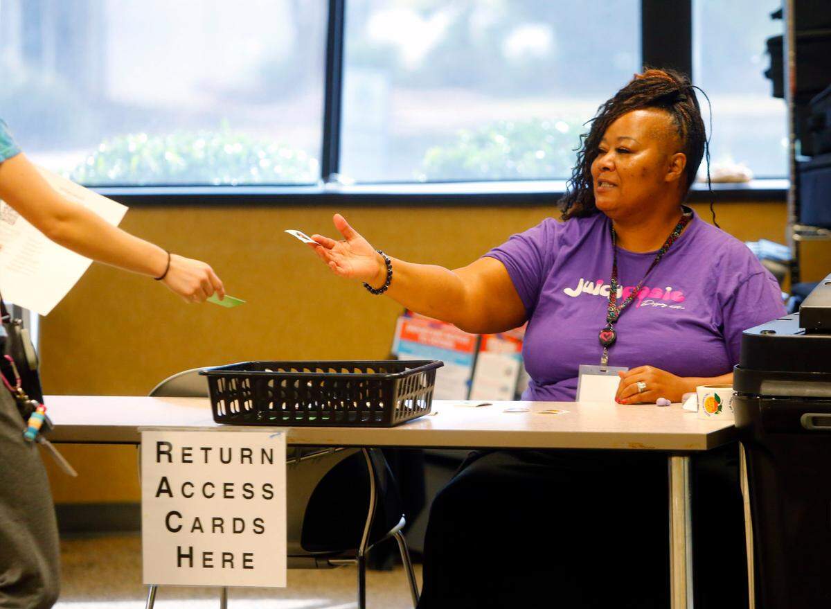 Jamysa Humphrey hands a “I’m a Georgia Voter” sticker to a voter who voted Tuesday morning at Columbus Technical College in Columbus, Georgia. 11-05/2024