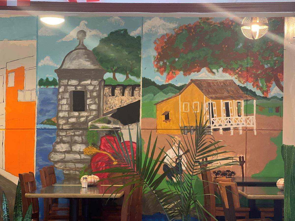 The mural being painted by Janiece Veguilla in La Garita Restaurant & Bakery represents elements of Puerto Rican culture and history.
